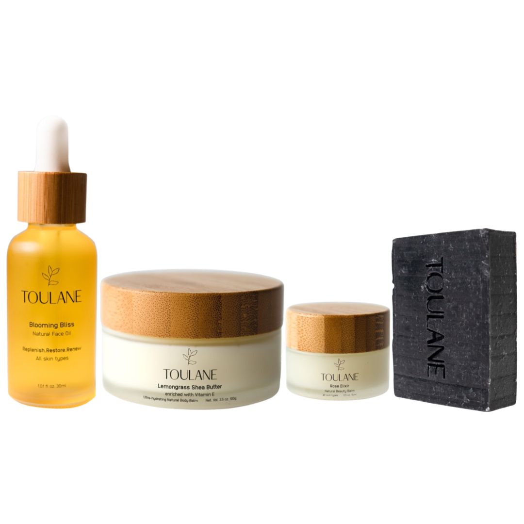A gift set by TOLUANE, containing a face oil, beauty balm, shea butter, and a soap bar, neatly arranged in a box with compartments for each item.
